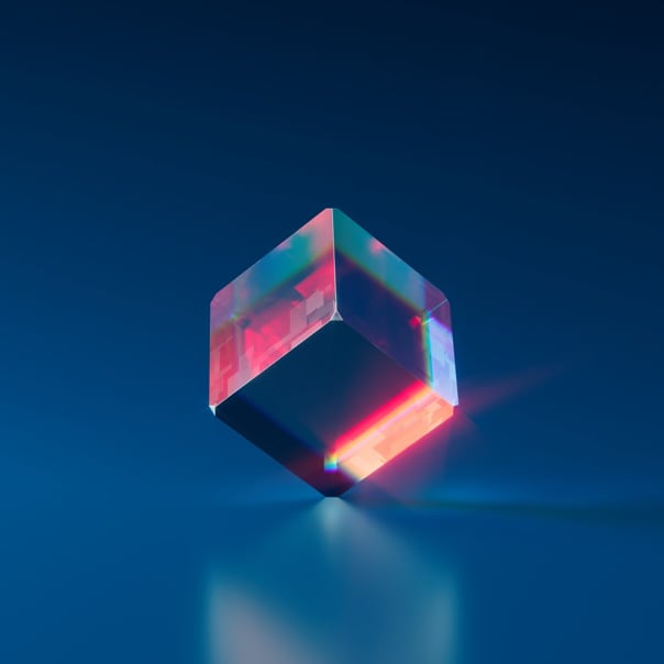 A glass-like cube that is rainbow colored and turned at an angle in a blue room.